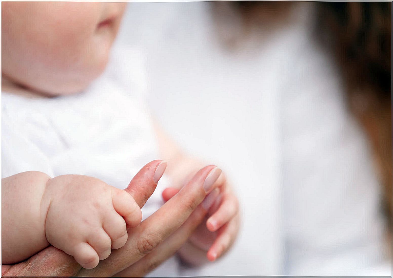 Baby holding his mother's finger.