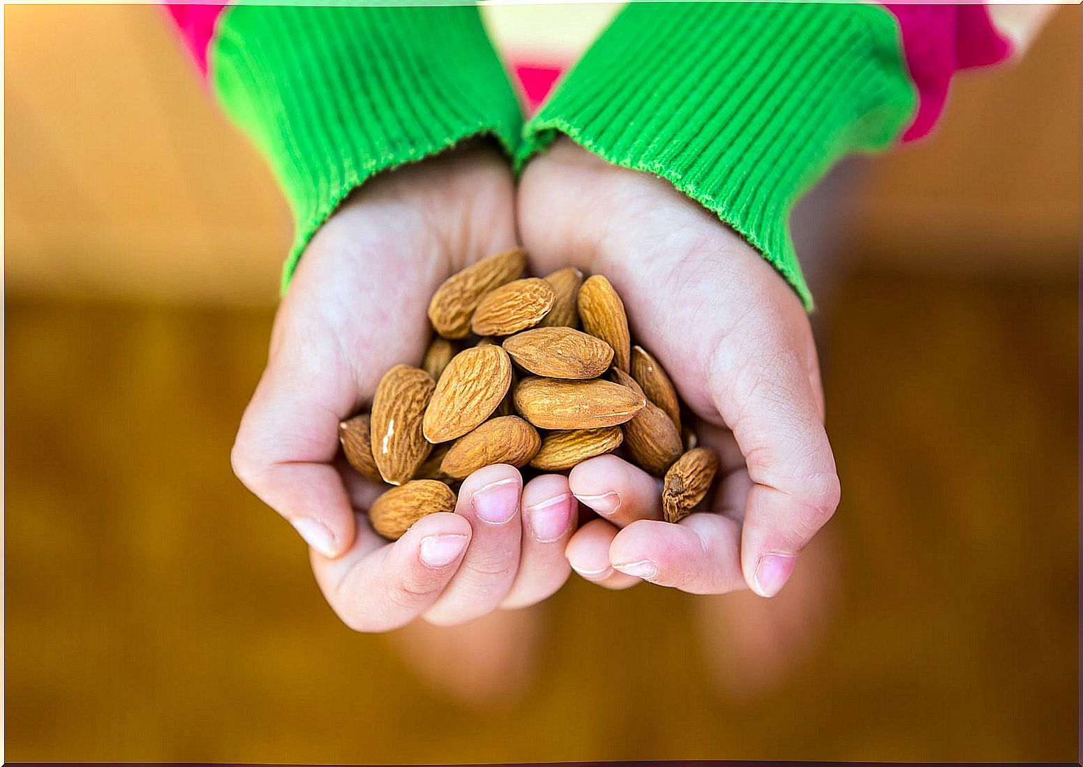 Child with hands full of almonds.