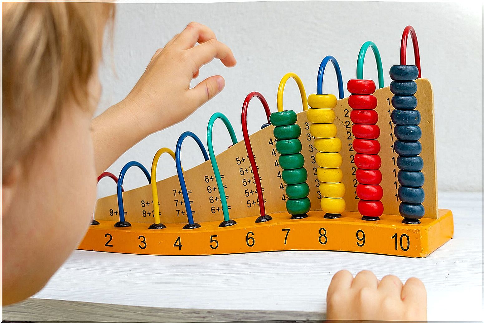 Child learning early mathematics with an abacus thanks to the Montessori method.