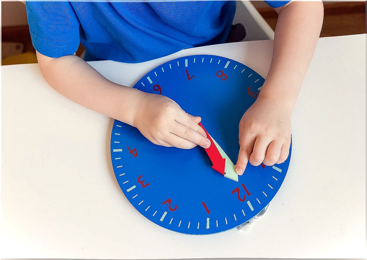 Child learning mathematics with a clock thanks to the Montessori method.