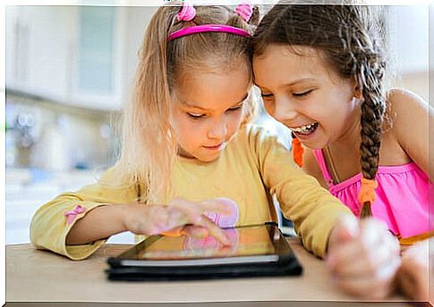 Two girls playing online with a tablet.