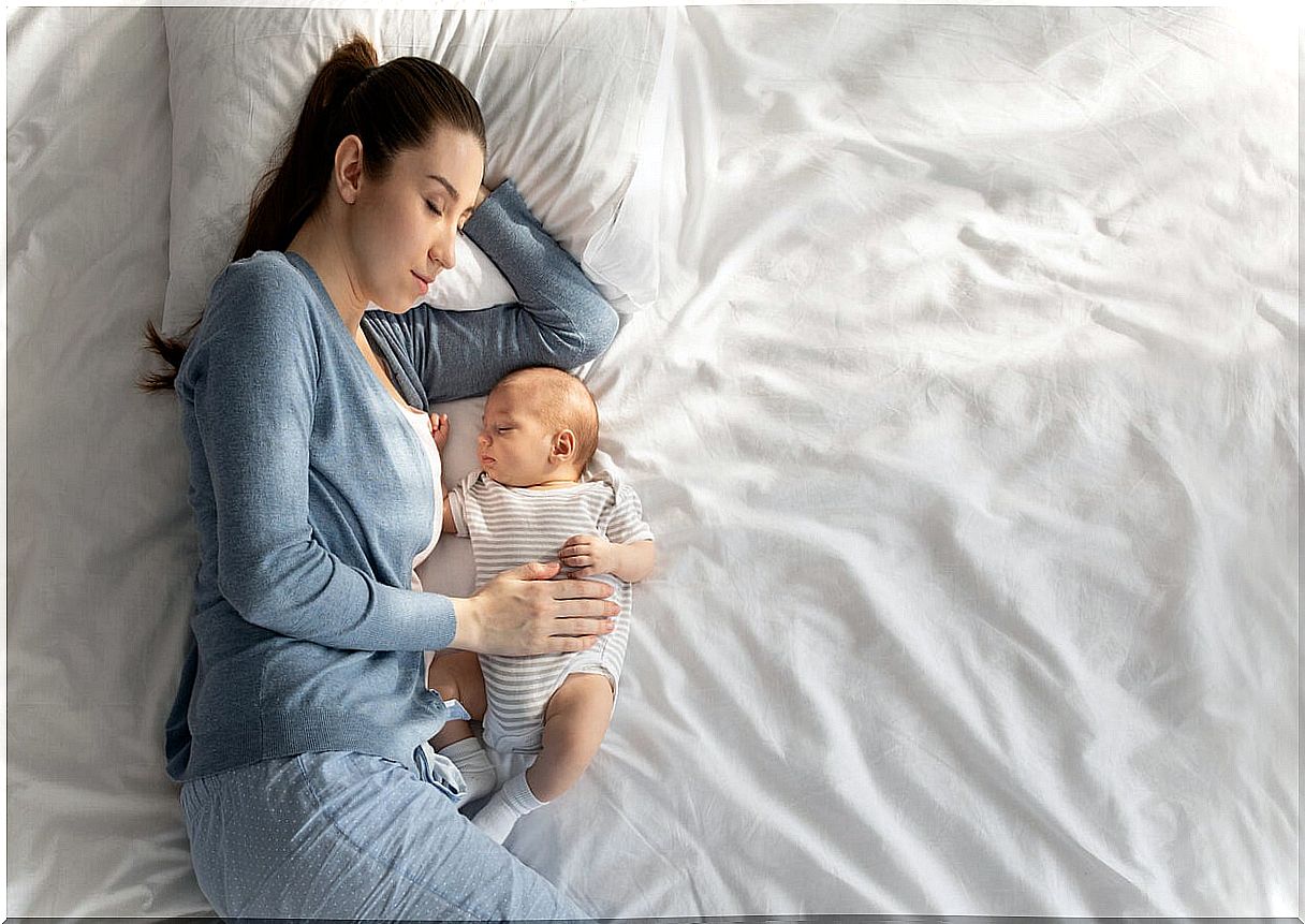 Mother doing co-sleeping and cuddling with her baby.