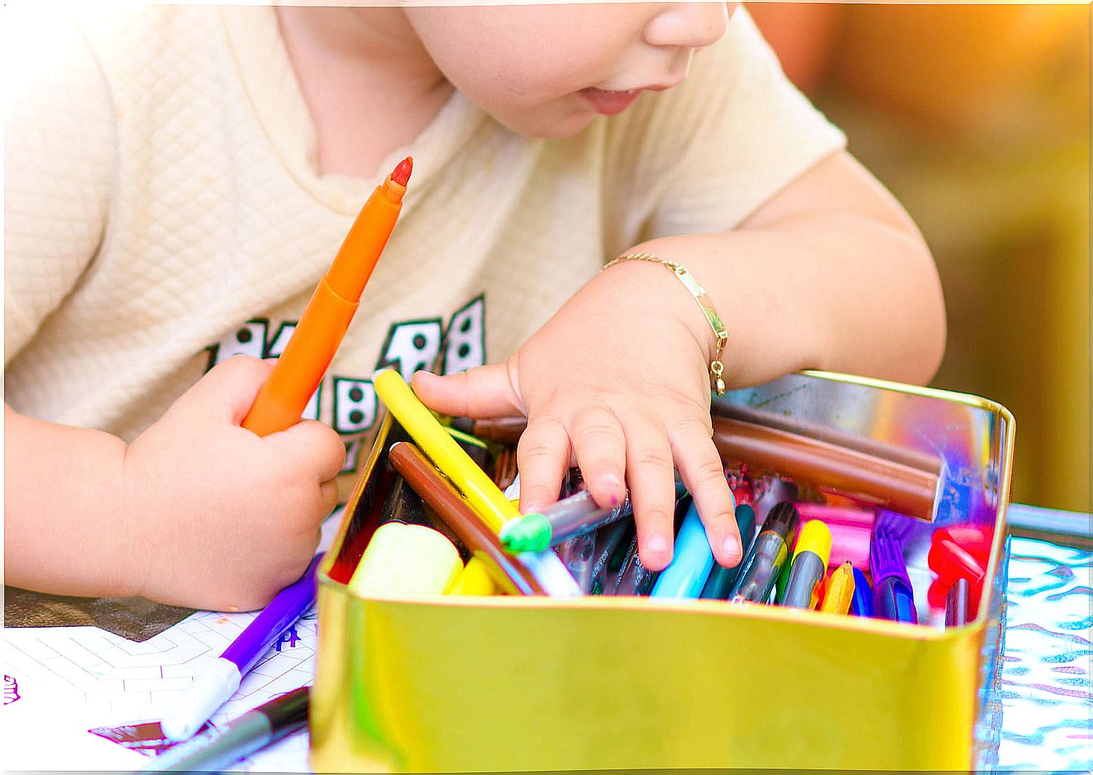 Child making a drawing with colored markers.