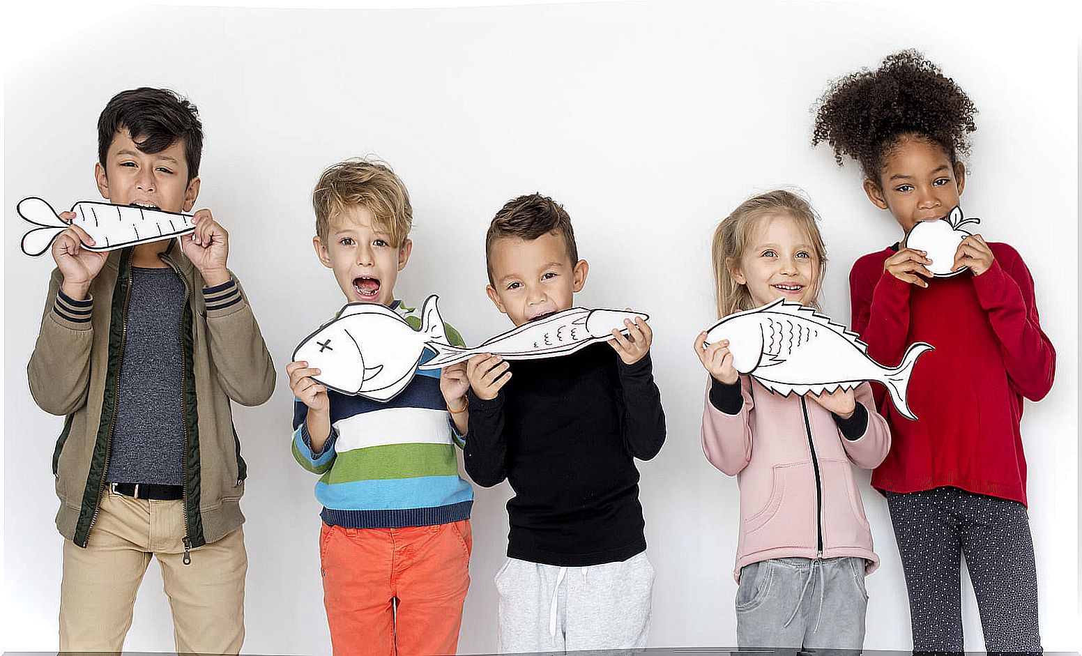 Children eating pictures of fish and fruits and vegetables.