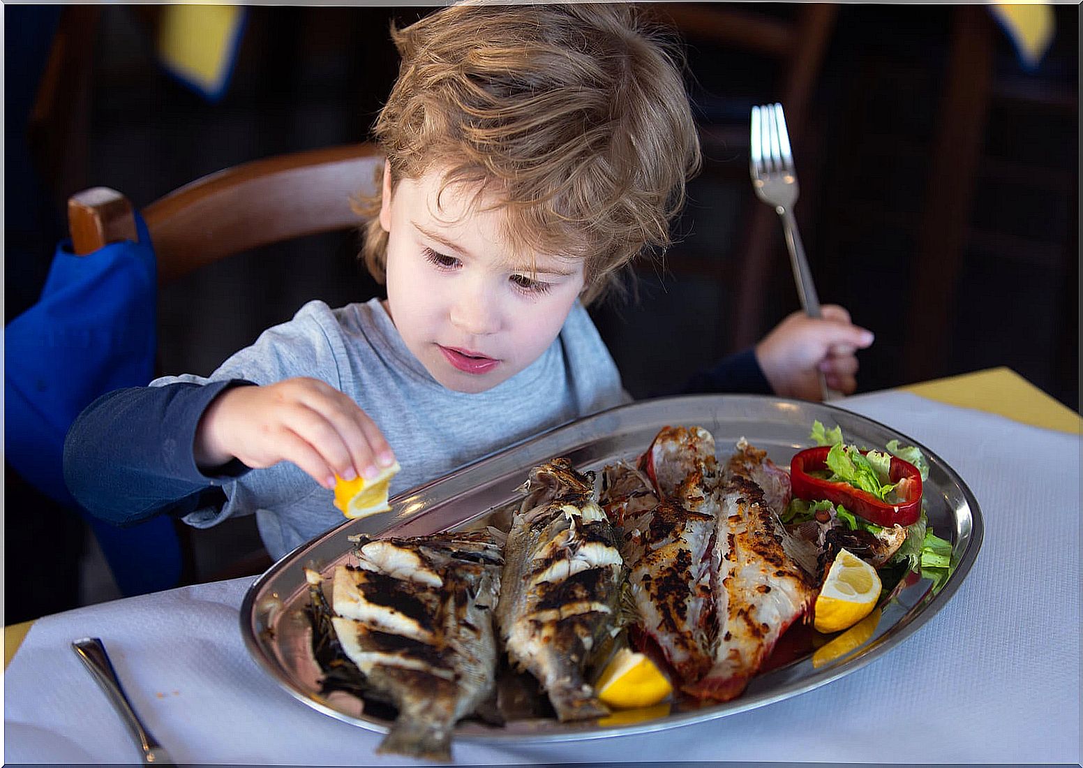 Child eating fish because it is very important in infant feeding.