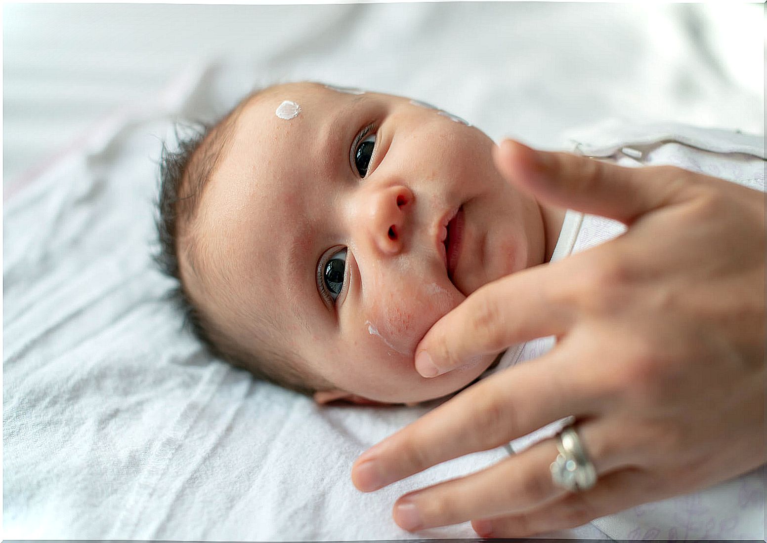 Mom putting cream on her baby's face.