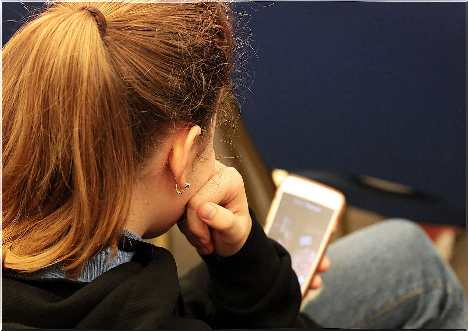 Teenager addicted to mobile phone consulting his social networks.