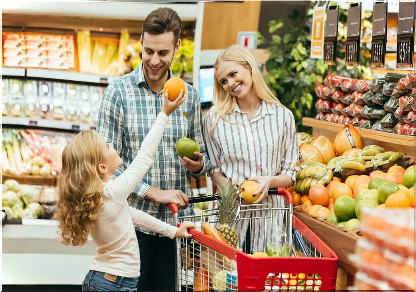 Parents buying fruit at the supermarket with their daughter to learn math.