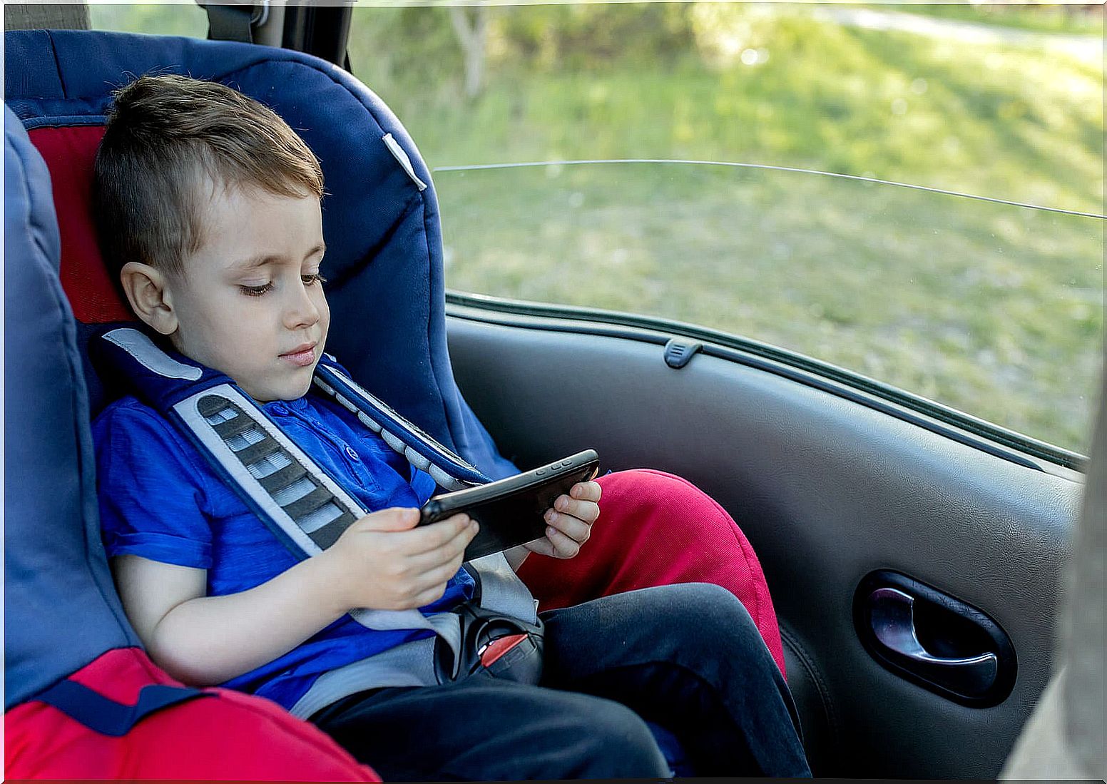 Child watching a movie on the tablet, one of the activities to do during long car trips.