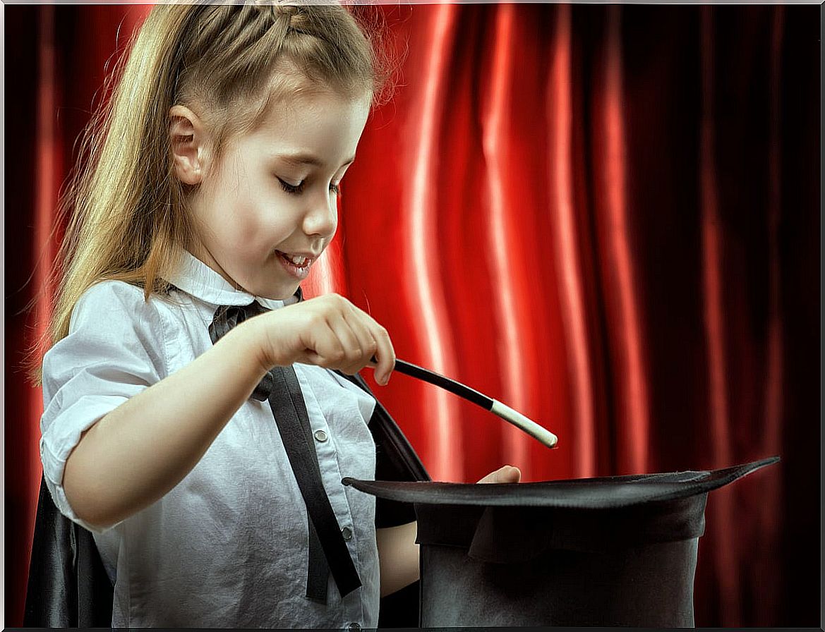 Little girl doing magic with a top hat.