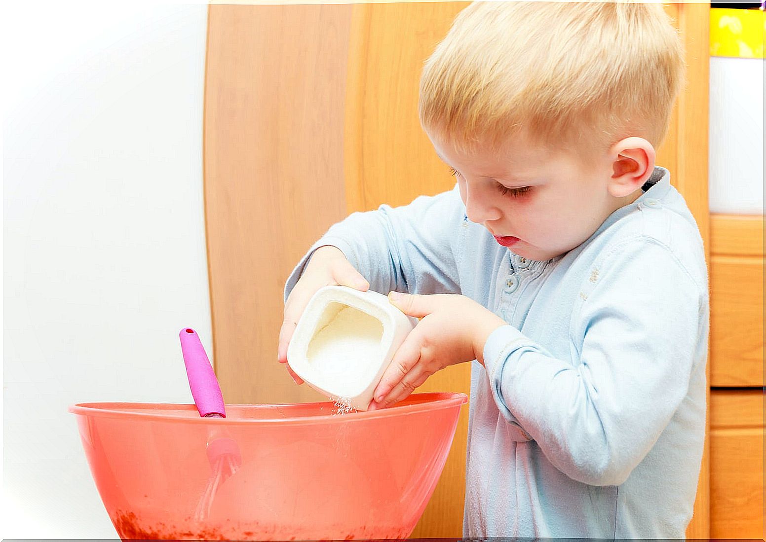 Child adding sweetener and sugar to a sponge cake.