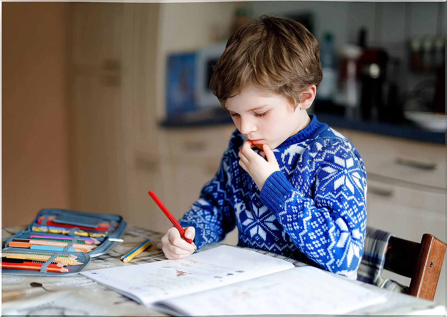 Child doing homework at home without free time, one of the dangers of wanting perfect children.