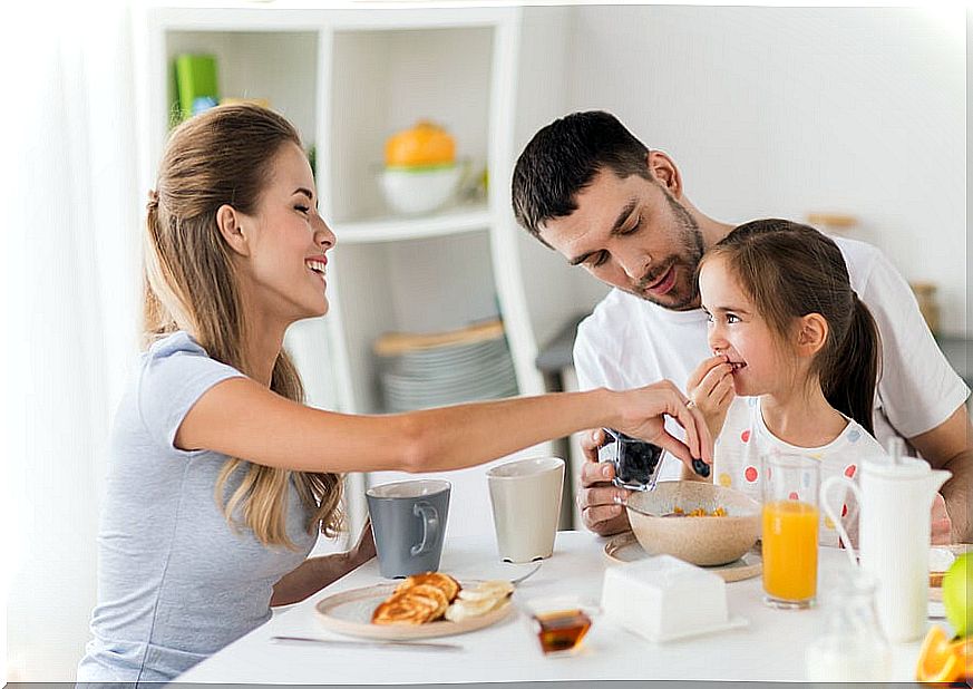 Mother and father having breakfast happily with their daughter.