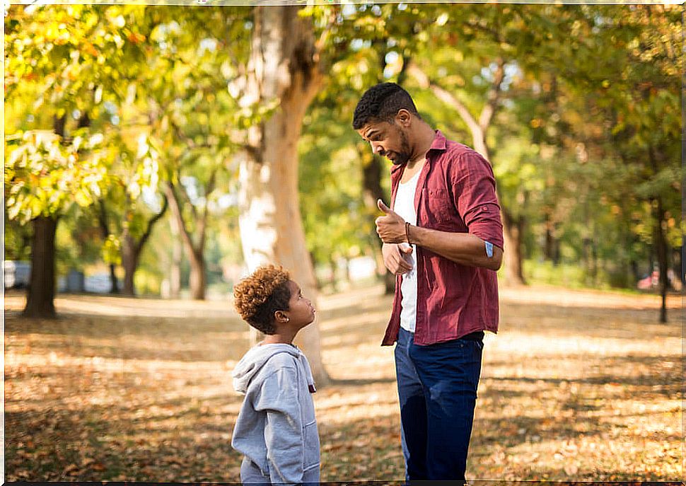 Father talking to his son about positive discipline in the park.