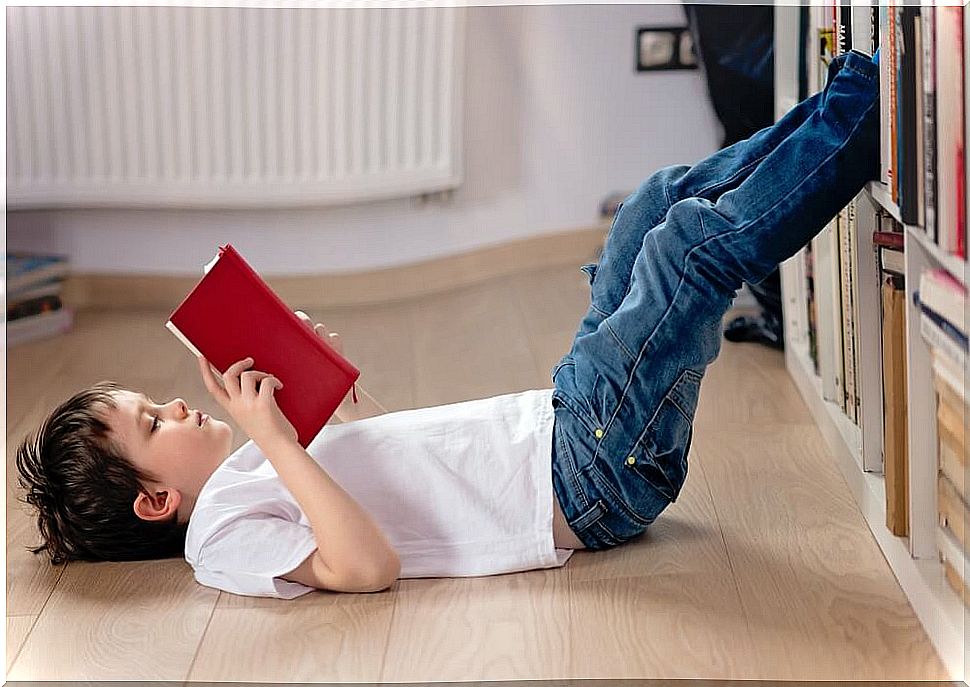 Boy reading a book lying on the floor during quarantine.